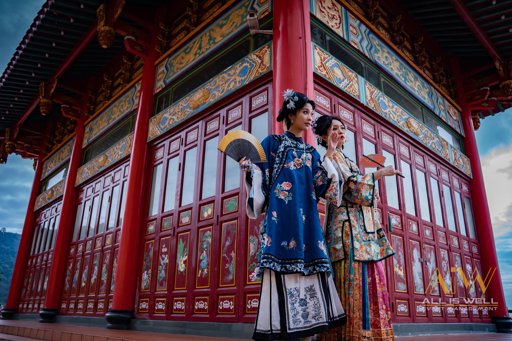 Two women in traditional dress at a red temple