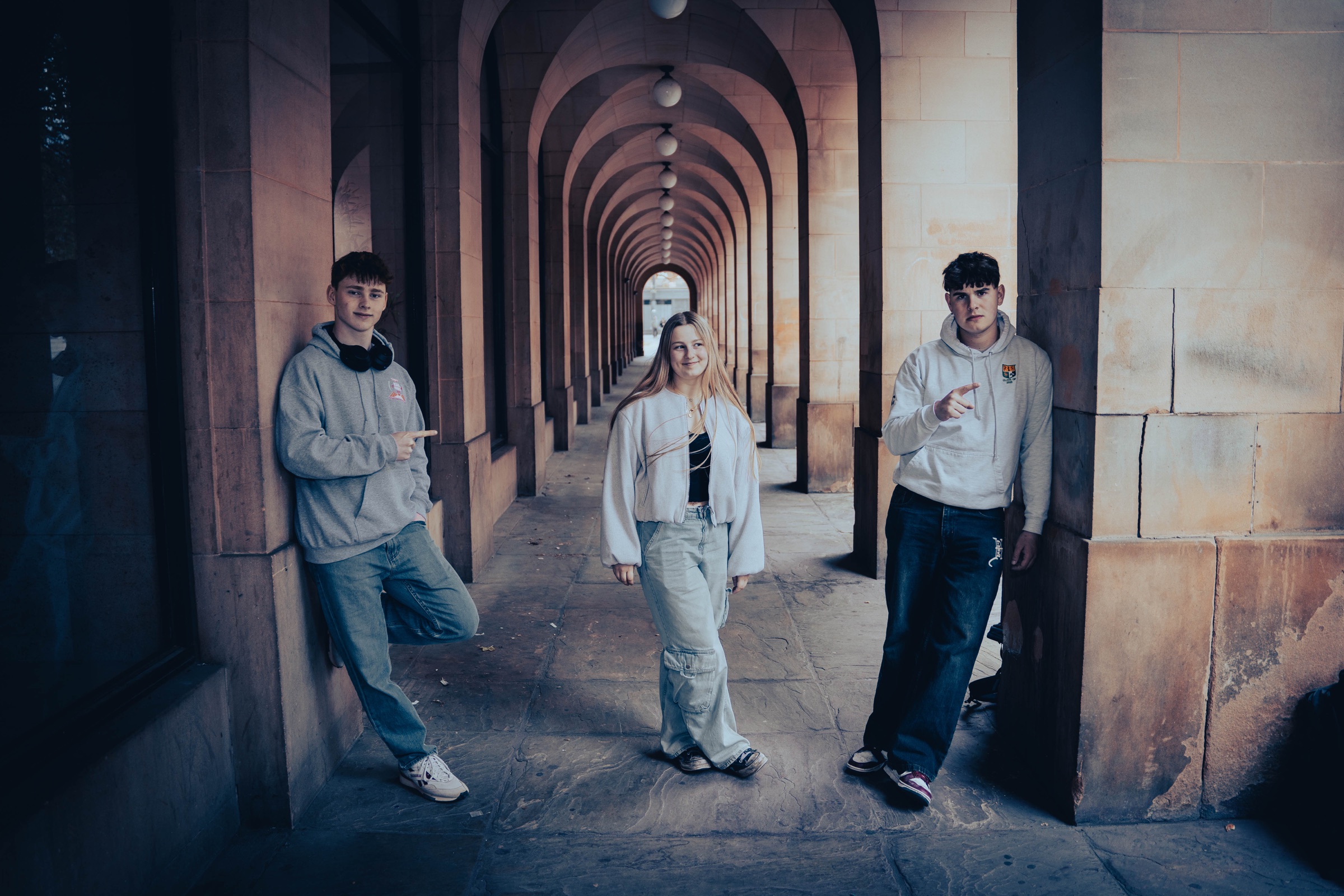 Three friends posing in a vaulted stone arcade