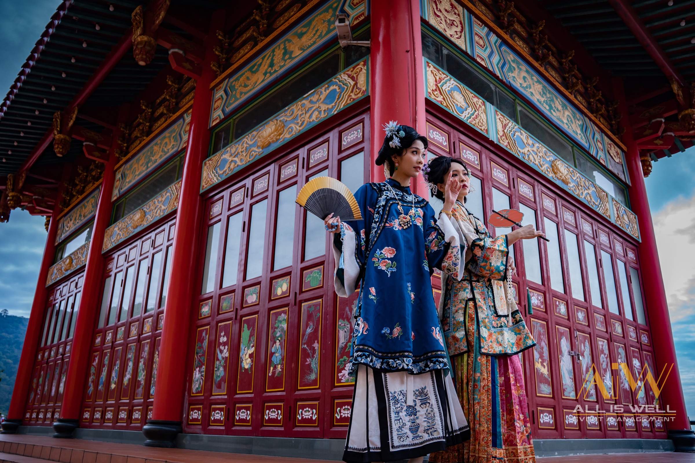Two women in traditional dress at an ornate red temple