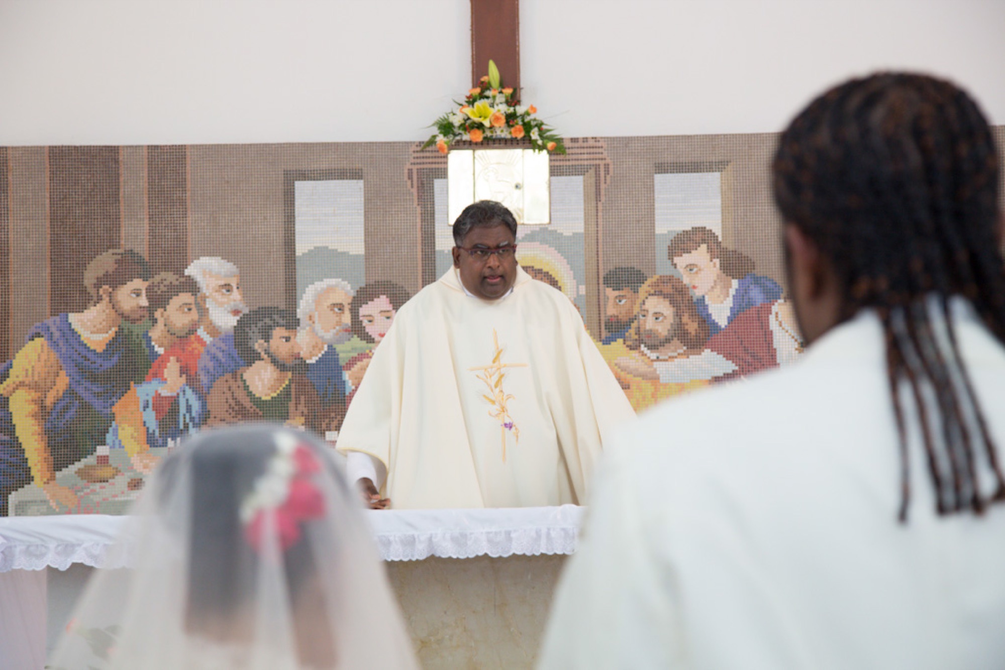 Priest officiating at the altar as the couple looks on
