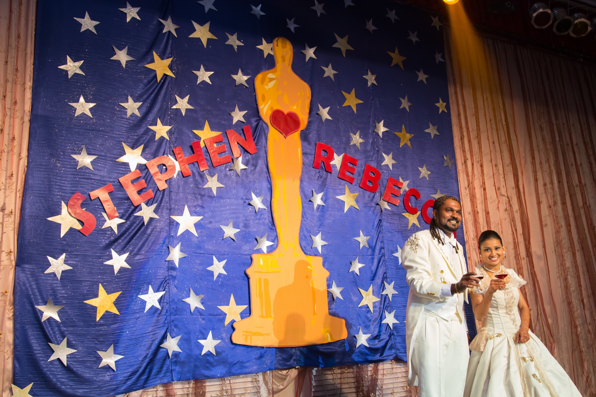 Couple toasting in front of their reception backdrop